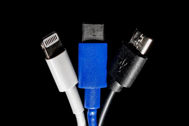 Three charging cords against a black background - a white lighting charger on the left, a blue USB-C charger in the middle and a black mini USB cable on the right.